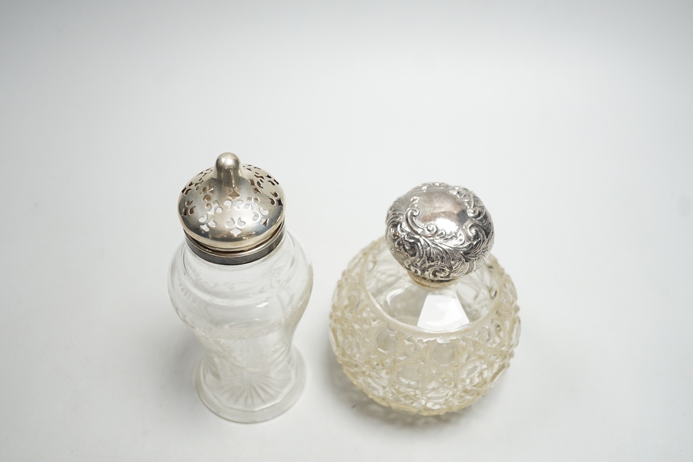 A late Victorian repousse silver mounted cut glass scent bottle, Chester, 1900, 13cm and a silver mounted sugar caster.